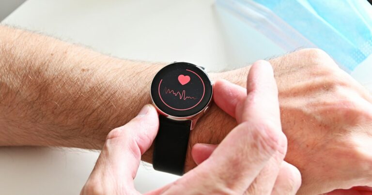 Smartwatch displaying a heart symbol and waveform on a wrist