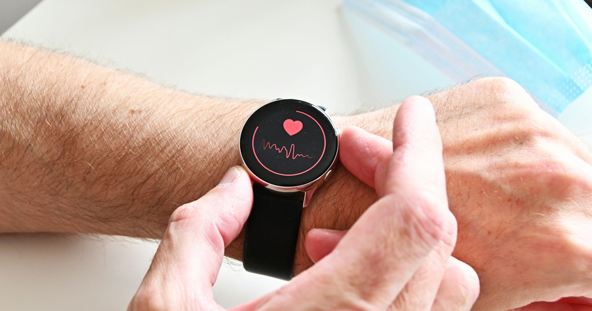 Smartwatch displaying a heart symbol and waveform on a wrist